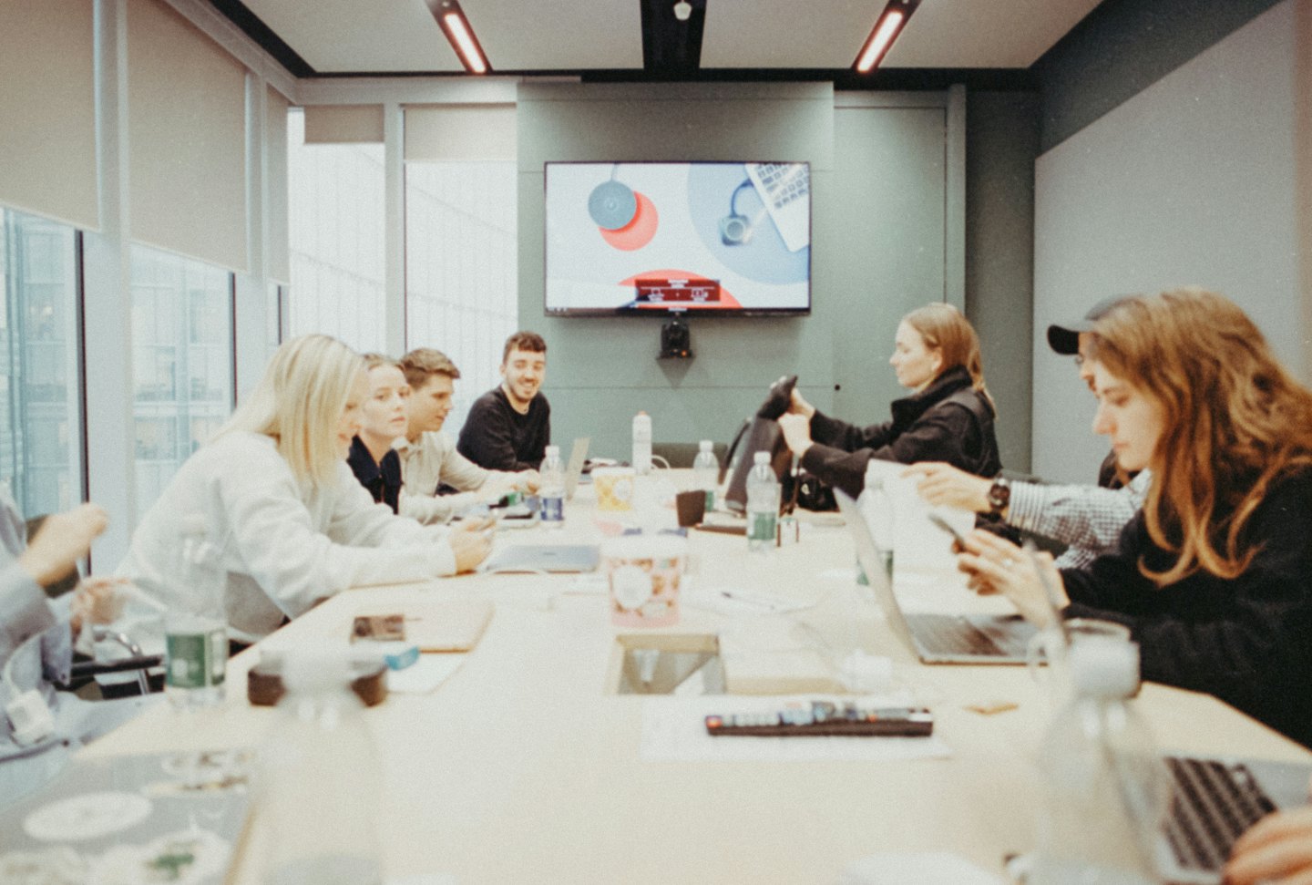 Professionals collaborating around a conference table with laptops.