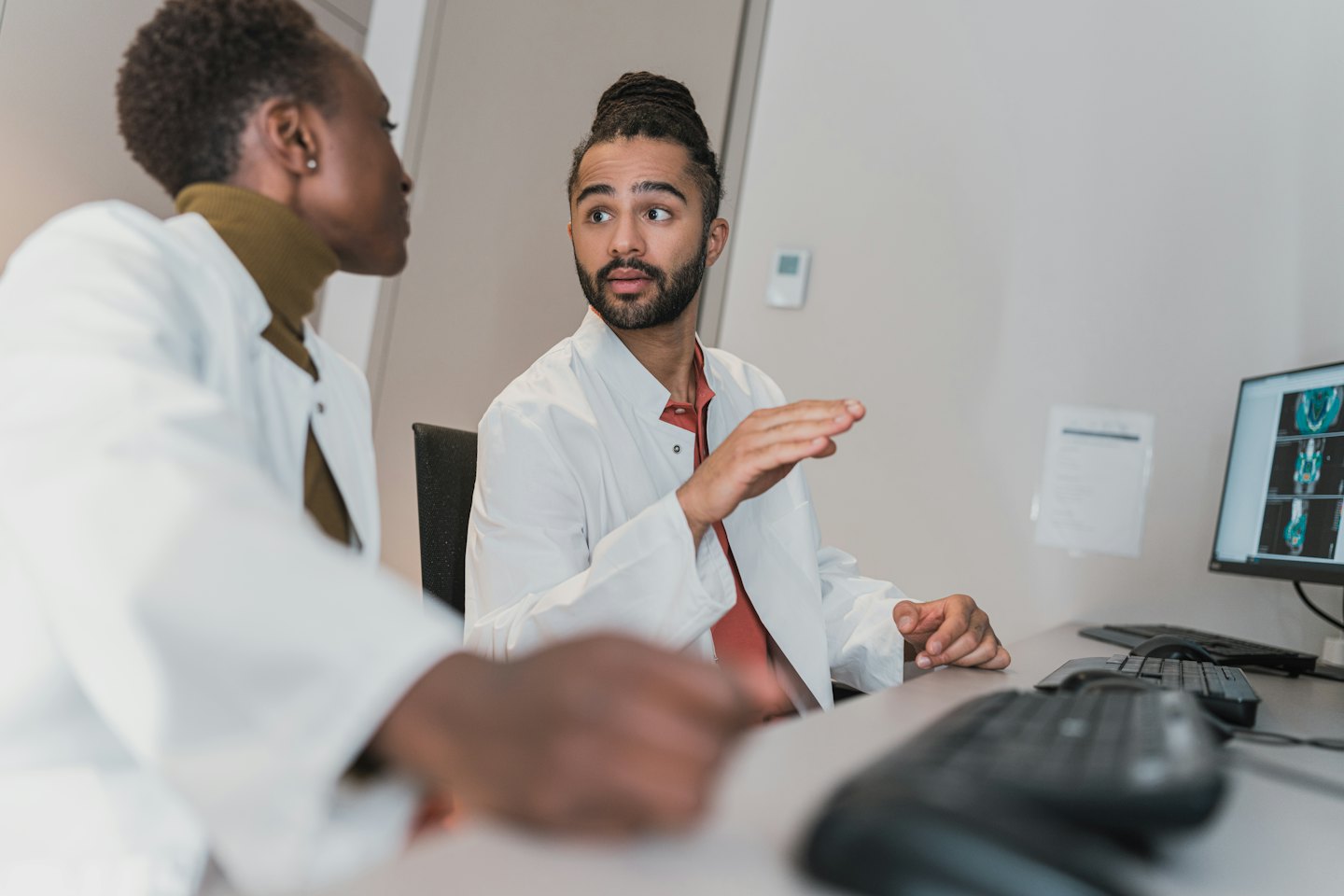 Medical professionals discussing scans on a computer screen.