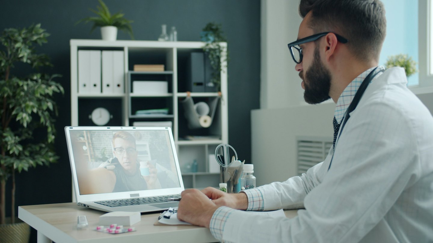 Doctor talks to a patient on a laptop during telemedicine call.